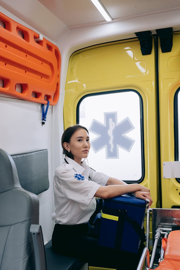 Asian female paramedic sitting inside an ambulance, ready for emergency response.